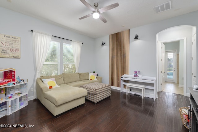 living room featuring baseboards, visible vents, arched walkways, ceiling fan, and wood finished floors