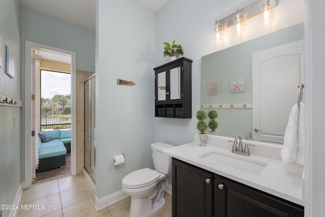 bathroom with toilet, vanity, baseboards, a shower stall, and tile patterned floors