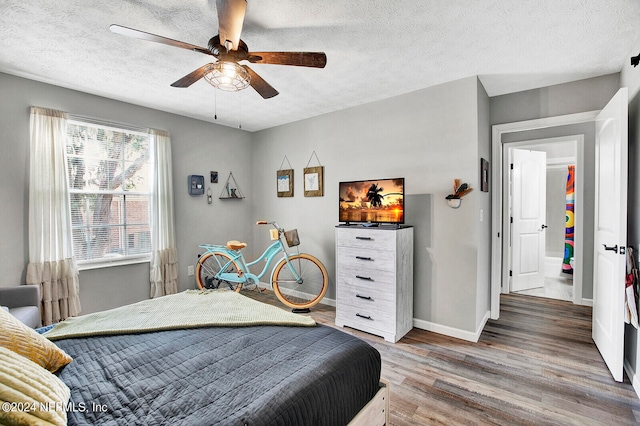 bedroom with a textured ceiling, ceiling fan, and hardwood / wood-style flooring