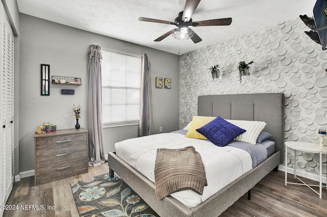 bedroom featuring a textured ceiling, a closet, ceiling fan, and wood-type flooring