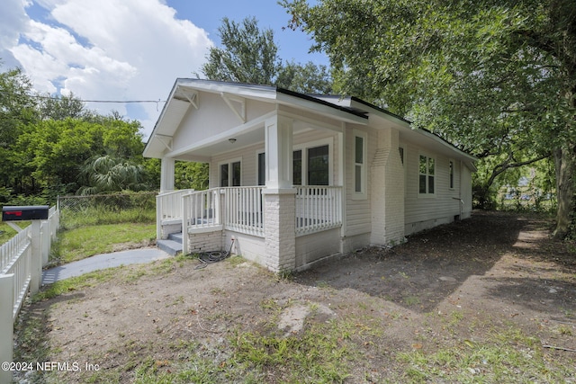 view of home's exterior featuring fence, a porch, and brick siding