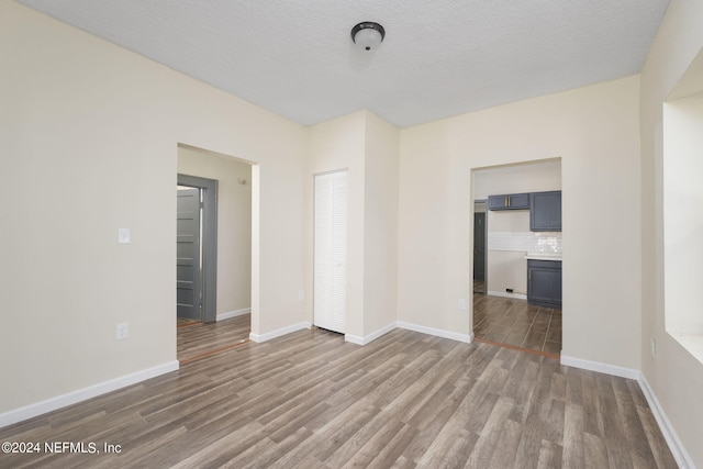 unfurnished bedroom with a textured ceiling, hardwood / wood-style flooring, and a closet