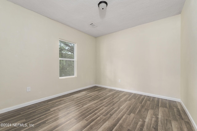 empty room with dark wood-style floors, a textured ceiling, and baseboards