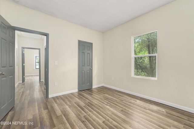 unfurnished bedroom featuring a textured ceiling, baseboards, and wood finished floors