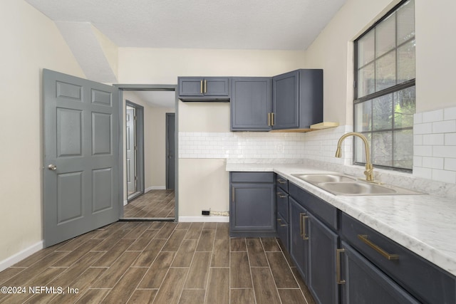 kitchen featuring dark wood-type flooring, tasteful backsplash, a textured ceiling, and sink