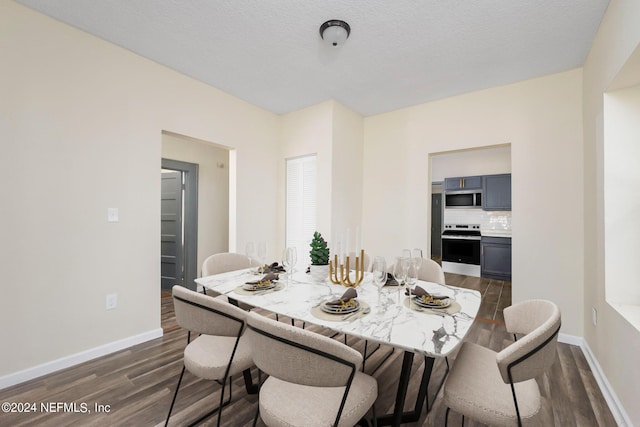 dining room with dark wood-style floors, a textured ceiling, and baseboards