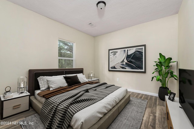 bedroom with baseboards, dark wood finished floors, and a textured ceiling