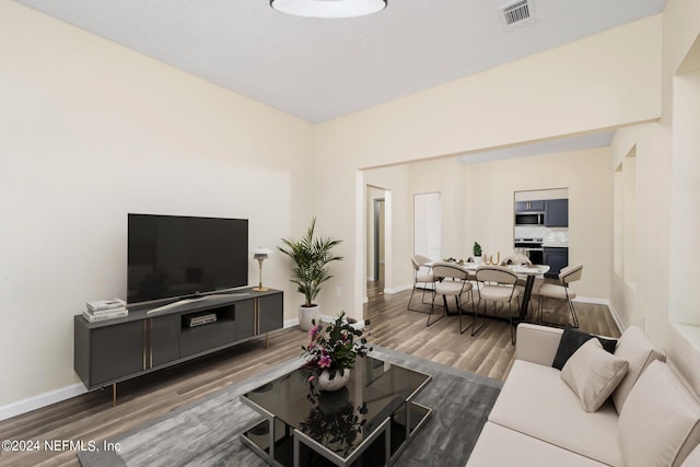 living room with visible vents, baseboards, and wood finished floors