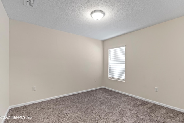 carpeted empty room featuring baseboards, visible vents, and a textured ceiling