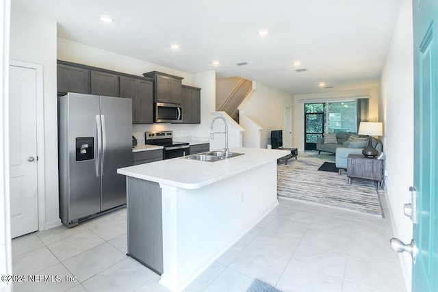 kitchen featuring light tile patterned floors, appliances with stainless steel finishes, an island with sink, and sink