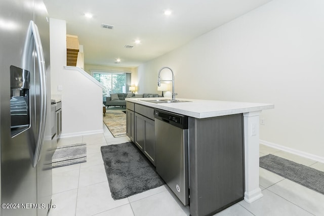 kitchen featuring appliances with stainless steel finishes, sink, light tile patterned flooring, and a kitchen island with sink