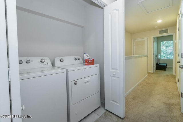 clothes washing area featuring light colored carpet and separate washer and dryer