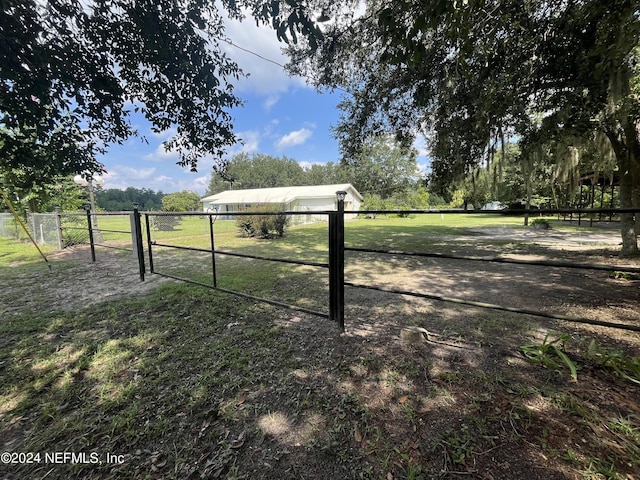 view of yard featuring a rural view, fence, and a gate