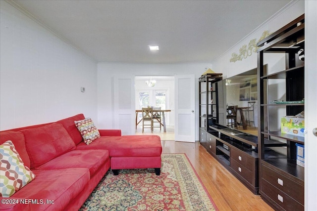 living room with an inviting chandelier, crown molding, and wood finished floors