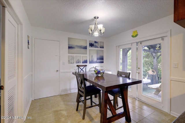 dining space featuring light tile patterned floors, a chandelier, a textured ceiling, and french doors