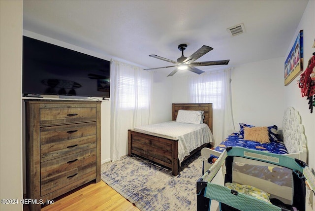 bedroom with light wood-style floors, visible vents, and a ceiling fan