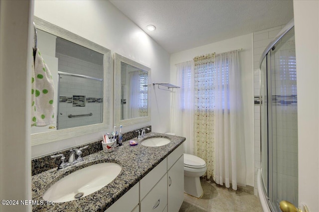 full bathroom featuring a stall shower, a sink, a textured ceiling, and toilet