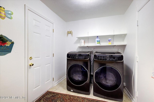 laundry room featuring washing machine and clothes dryer, a textured ceiling, tile patterned flooring, laundry area, and baseboards