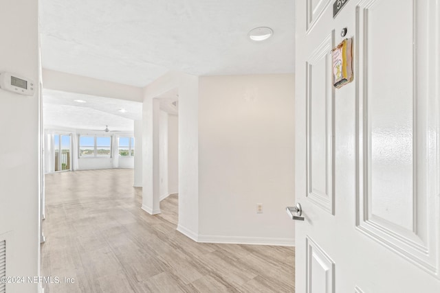 hall featuring light wood-style flooring and baseboards