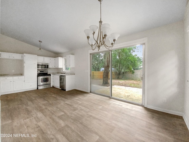 unfurnished living room with a notable chandelier, vaulted ceiling, hardwood / wood-style flooring, and a healthy amount of sunlight