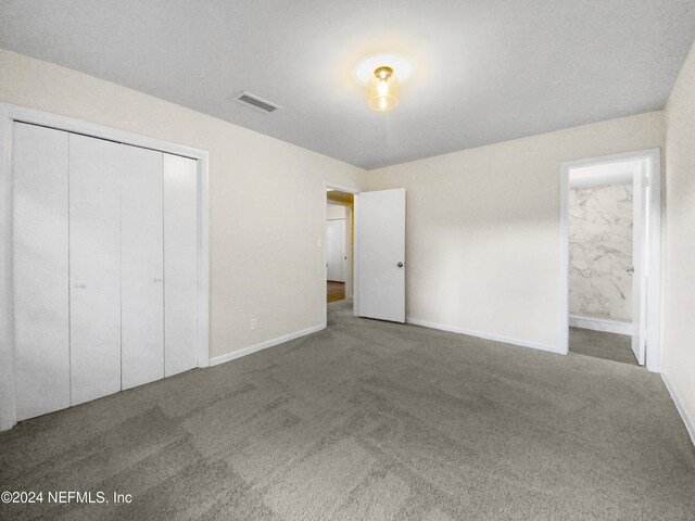 unfurnished bedroom featuring ensuite bath, a closet, and carpet