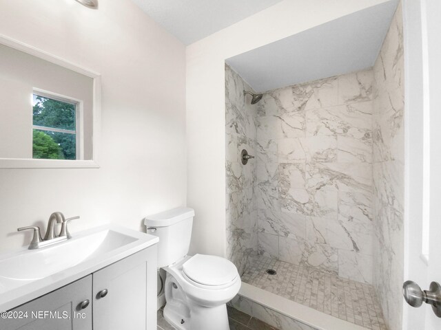 bathroom featuring vanity, a tile shower, and toilet