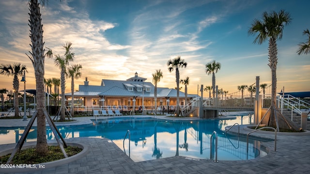 pool at dusk featuring a patio area, a community pool, and fence