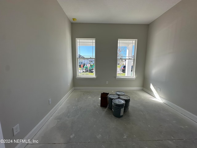 unfurnished room with concrete flooring and a textured ceiling