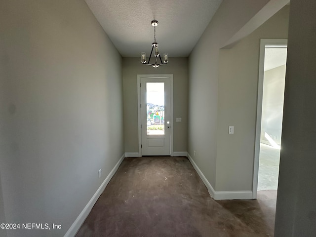 entryway with dark carpet, a textured ceiling, and an inviting chandelier