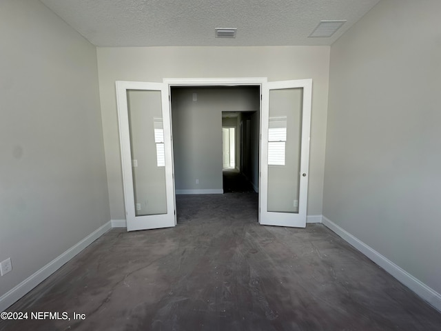 spare room with french doors, a textured ceiling, and dark hardwood / wood-style floors