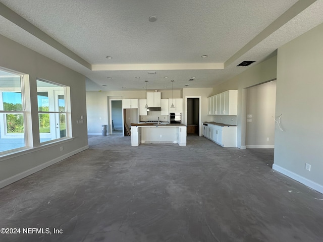 unfurnished living room featuring a raised ceiling and a textured ceiling