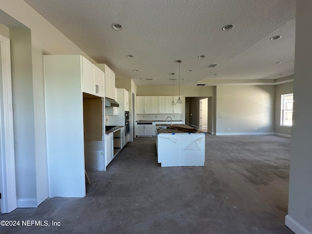 kitchen with white cabinetry, sink, an island with sink, pendant lighting, and a textured ceiling