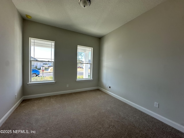 empty room with a textured ceiling, carpet flooring, and baseboards