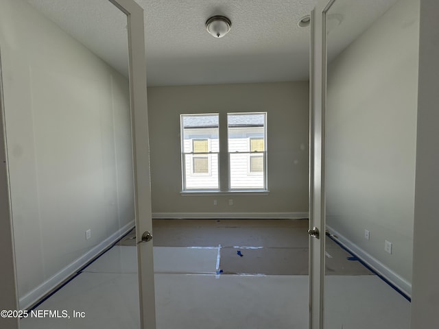 empty room featuring baseboards and a textured ceiling