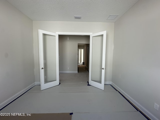 unfurnished room featuring finished concrete floors, visible vents, a textured ceiling, and baseboards