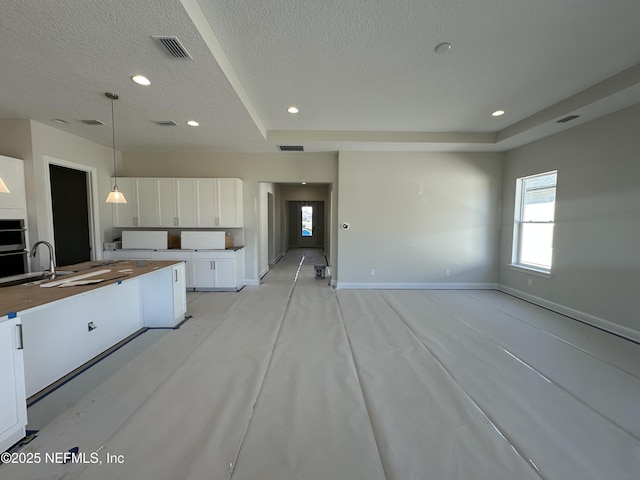 kitchen with baseboards, visible vents, white cabinets, a textured ceiling, and pendant lighting