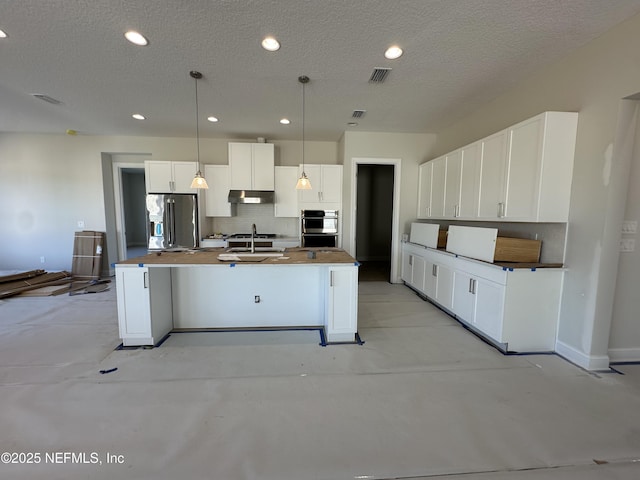 kitchen featuring hanging light fixtures, appliances with stainless steel finishes, an island with sink, and white cabinets