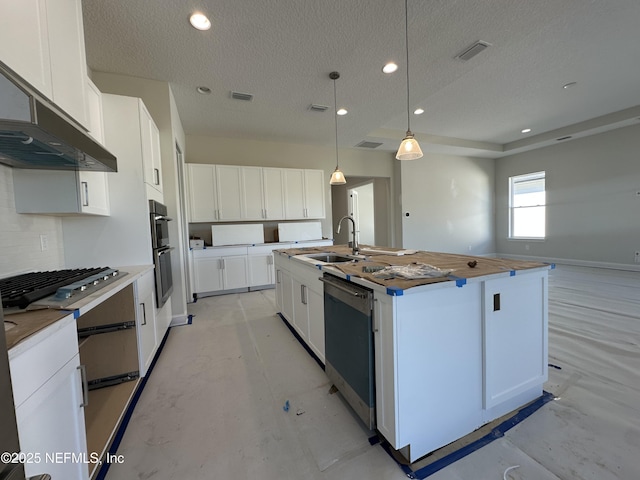 kitchen with stainless steel appliances, hanging light fixtures, white cabinets, a kitchen island with sink, and a sink