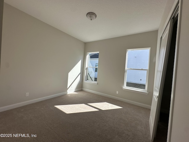 unfurnished room with baseboards, dark colored carpet, and a textured ceiling