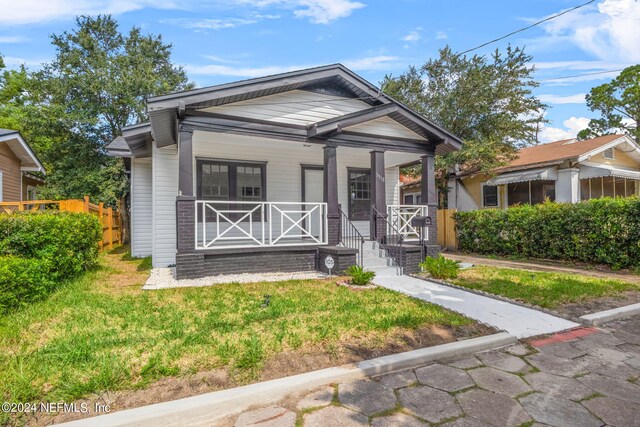 bungalow-style home featuring covered porch and a front yard