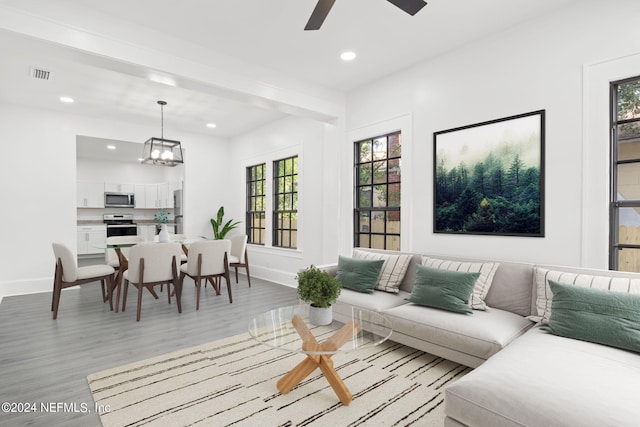 living room with ceiling fan with notable chandelier, light hardwood / wood-style flooring, and plenty of natural light