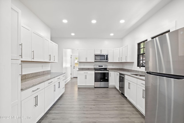 kitchen featuring sink, stainless steel appliances, light hardwood / wood-style floors, and white cabinetry