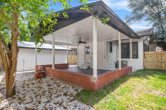 rear view of property featuring ceiling fan, a lawn, and a patio