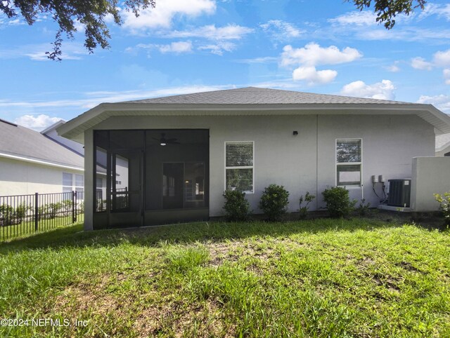 rear view of property featuring central air condition unit, a lawn, and a sunroom