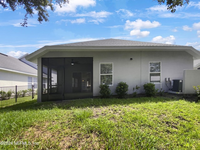 back of house featuring central AC unit, a sunroom, and a lawn