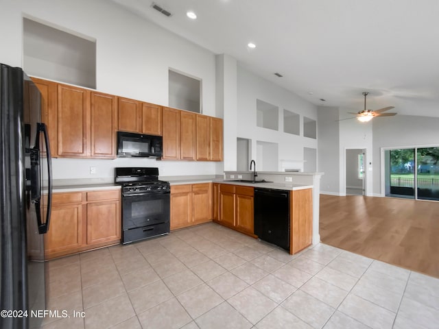 kitchen featuring high vaulted ceiling, light hardwood / wood-style floors, black appliances, sink, and kitchen peninsula