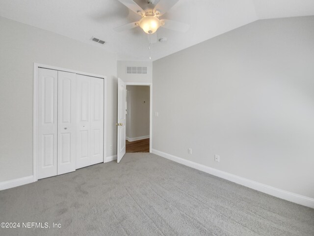 unfurnished bedroom featuring lofted ceiling, carpet flooring, a closet, and ceiling fan