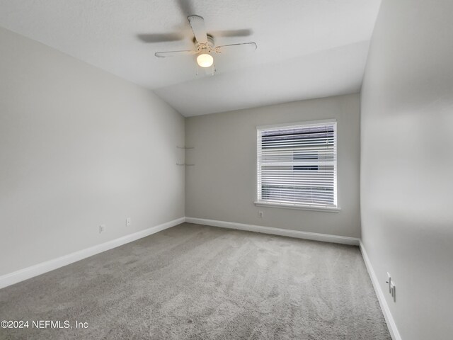 spare room featuring ceiling fan, vaulted ceiling, and carpet flooring