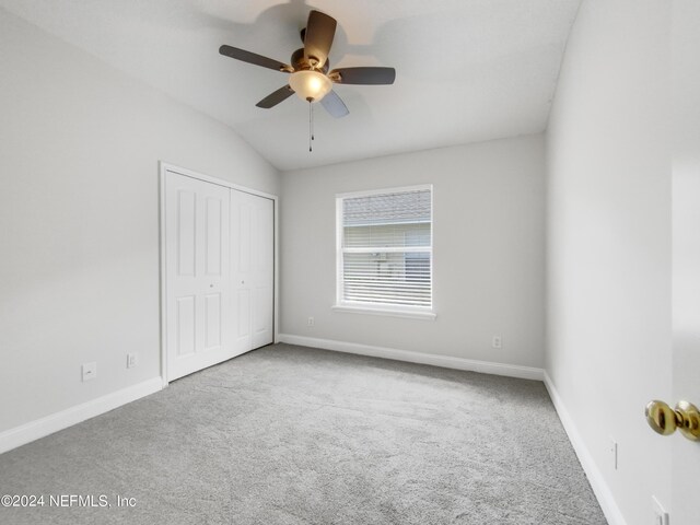 unfurnished bedroom featuring ceiling fan, carpet floors, a closet, and lofted ceiling