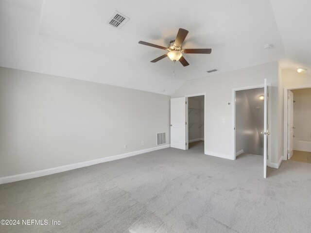 unfurnished bedroom with ceiling fan, a walk in closet, connected bathroom, and carpet